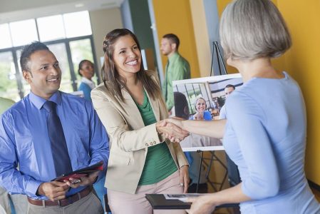 Woman shaking hands with professional executive at job fair event